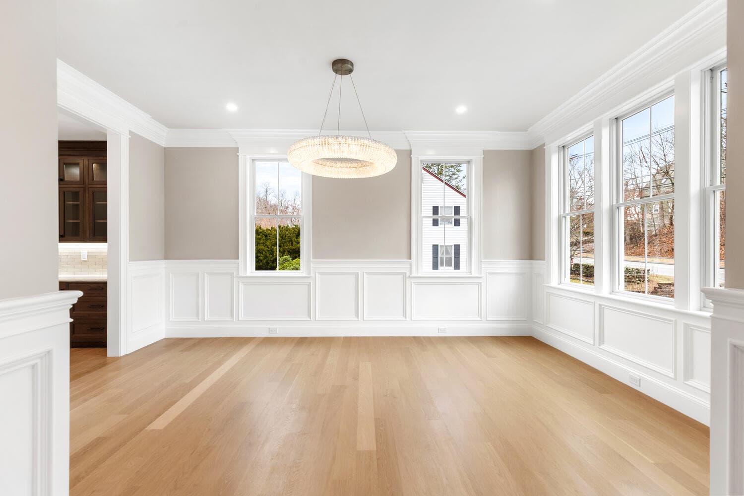 Formal dining room with wainscoting, crystal chandelier, and expansive windows