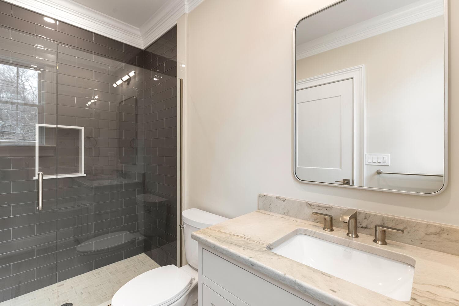 Ensuite bathroom with dark tile shower and marble vanity