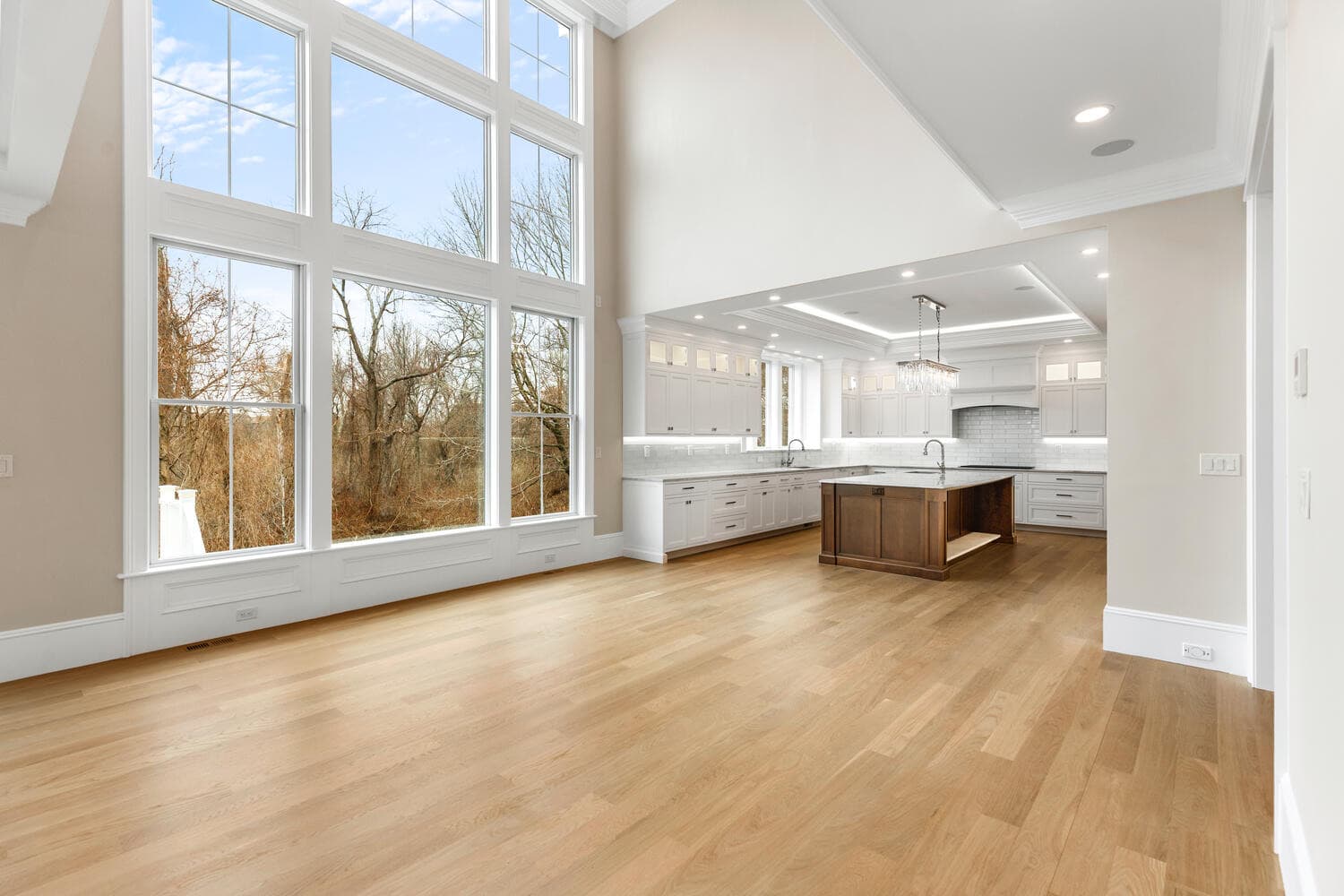 Great room with 19-foot ceilings, two-story window wall, and open connection to kitchen