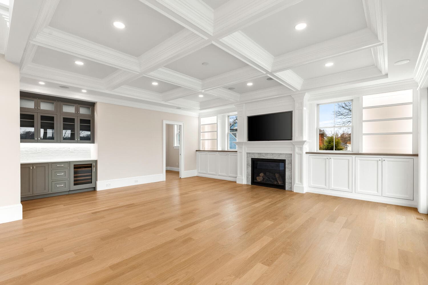 Living room with coffered ceiling, fireplace, wine fridge, and built-in cabinetry