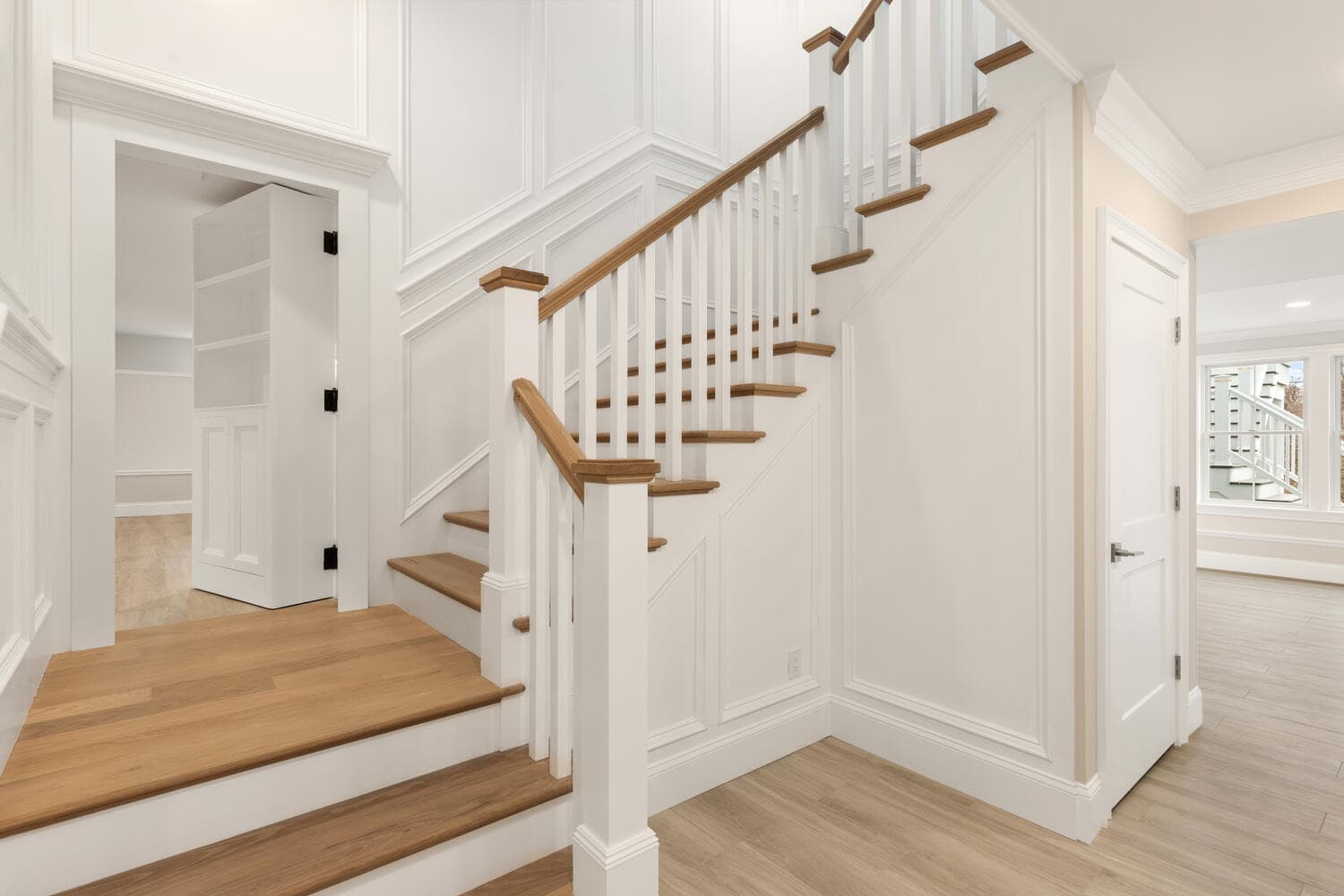 Lower level staircase with hidden secret room door and wainscoting
