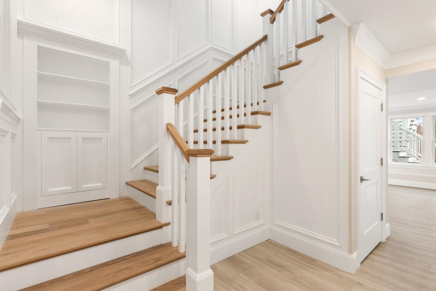 Staircase with oak treads, white spindles, dark oak handrail, and wainscoting