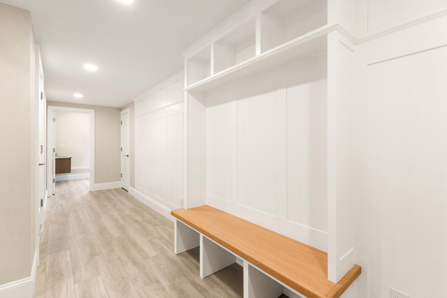 Mudroom with built-in storage, wood bench, and white cabinetry