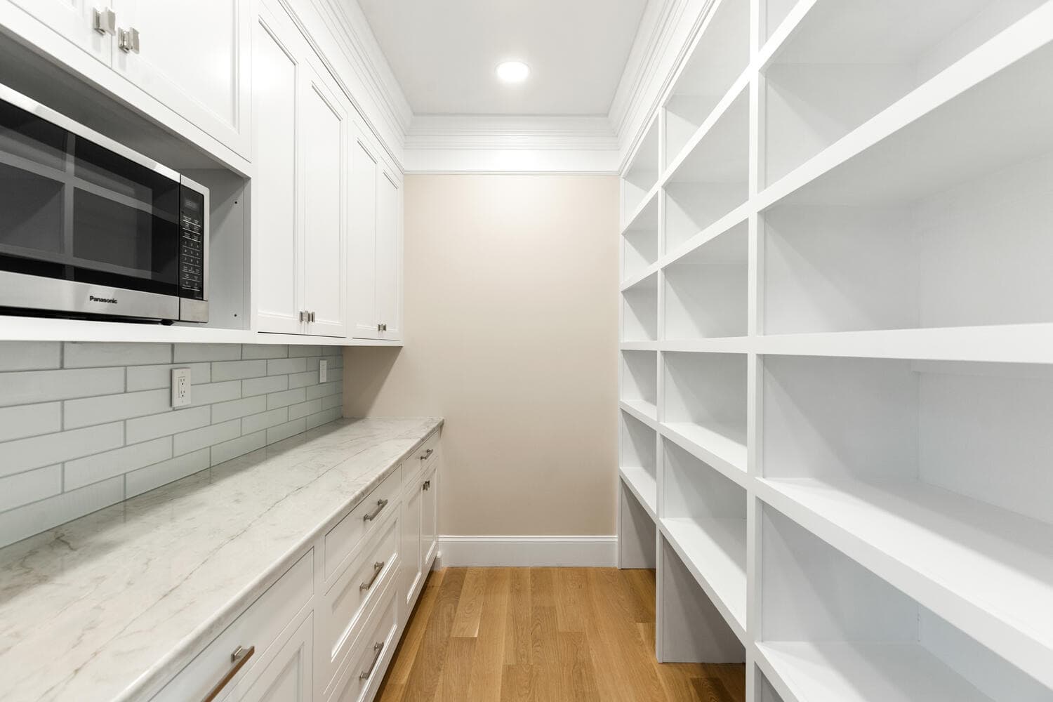 Chef's pantry with white cabinetry, subway tile backsplash, and marble counter
