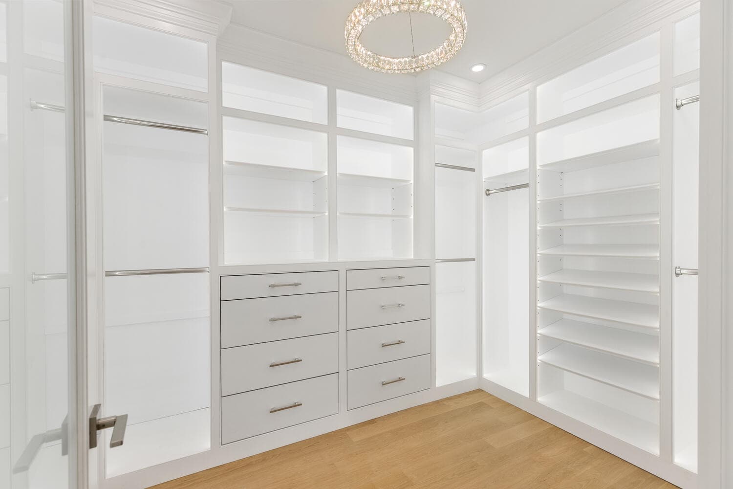 Primary walk-in closet with crystal chandelier and custom built-ins